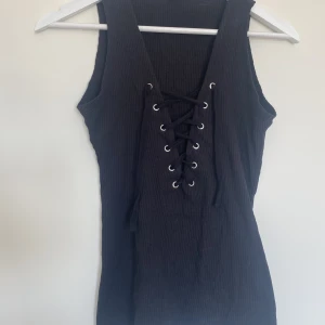 Lite längre linne - Linne med snörning fram från GinaTricot. Fint skick, använt fåtal gånger. 