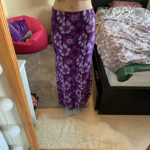 Lila omlott maxikjol  - Super söt maxi och omlottkjol som passar till de flesta storlekar då den knyts i midjan. Banden i midjan är långa så kan justeras mycket. Är lila med blommor. Köpt secundhand men bra skick! Tryck gärna på köp nu!! :)