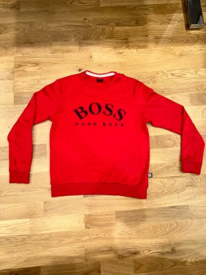 Hugo Boss Red Sweatshirt  - Fräsch och nästan helt oanvänd Hugo Boss sweatshirt av bästa kvalitet. Fick i present för 1 månad sedan men är för liten för mig så säljer för billigt pris.