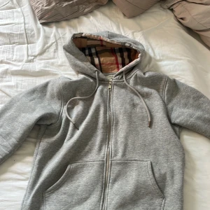 Burberry zip hoodie - Hej jag vill sälja min burberry zip för att jag e knaz me pengar men Den är storlek L som passar M och Den har en skön och varm passform på kroppen. Retail går för runt 6-7 lax mitt pris 1500