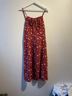 Blommig klänning - Blommig röd klänning med slits nere på vänstra benet den går typ ner till knäna väldigt fin till sommaren 