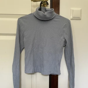 Blå turtleneck - Blå/grå turtleneck med dubbelvikt krage, tyget har randig textur men väldigt mjukt, har använt en del men använder inte längre