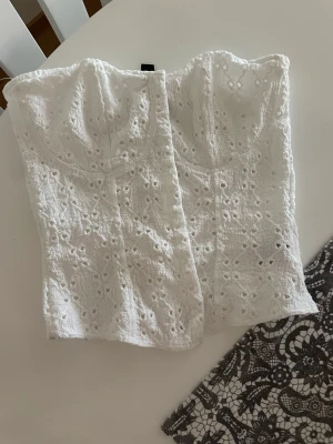 Korsett-topp från H&M - En vit korsett-topp från H&M, nyskick. Inköpt på H&M i Cypern i April. Säljes pga bröstoperation.