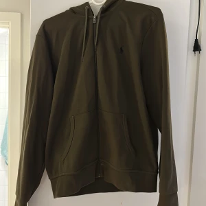 Ralph Lauren Zip tröja - Säljer min ralph lauren tröja då jag inte använder den längre. Köpte den i början på året. Tröjan är mörkgrön och är i storlek M. Jag betalar för frakten!