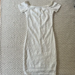 Vit spetsklänning - En kort, vit spetsklänning med off shoulder och även ett silikonband i kanten som gör att klänningen sitter på plats Frakt tillkommer 