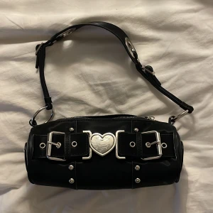 Y2K väska svart - skit söt svart y2k väska! köpt för drygt 2 år sen, nästan oanvänd. Mått: 24 cm x 10. Nypris ~900kr !!använd gärna köp nu!!