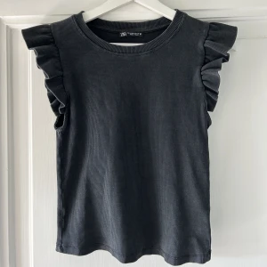 Topp - En topp från zara med volangdetaljer på ärmarna, i en fint grå färg 