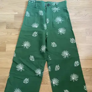 Gröna byxor med olika motiv av blad från Zara. Högmidjade och går ungefär till anklarna på mig som är 163. Helt oanvända. Storlek XS men små i storleken så passar även XXS. 