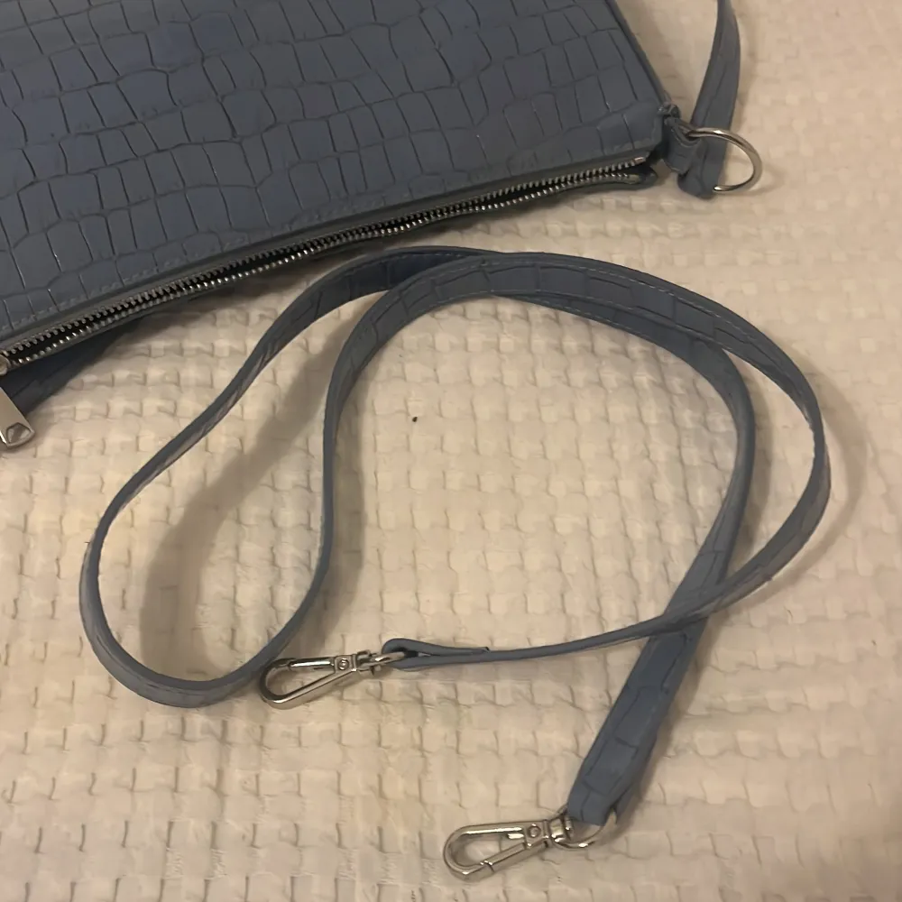 Den blå handväskan har ormskinn material (inte riktigt ormskinn). Den kommer från h&m och är i bra skick, inga skador på den eller något! Det gör till ett längre band till den ifall man skulle vilja ha det. . Väskor.