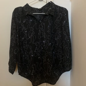 Skjorta från Monki - Skjorta/blus från Monki med ansiktsmönster. Korta ärmar.