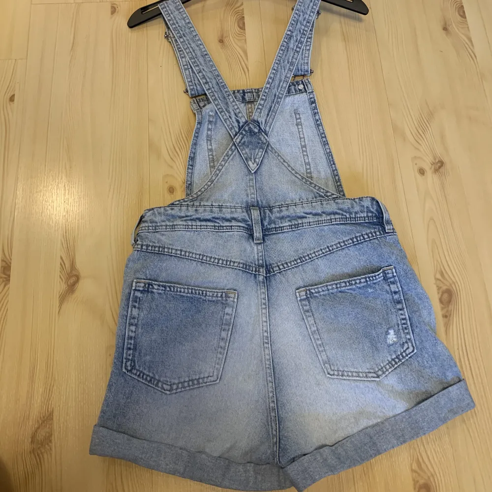 Skön byxdress i jeans från HM. Använd med inga slitningar alls och är i gott skick. Passar mig som är strl 36, men nu blivit för liten i låren då den är strl 34. Annars sitter den bra!. Jeans & Byxor.