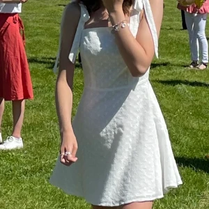 Superfin sommarklänning  - Vit superfin sommarklänning! Perfekt till student, midsommar eller annan festlighet! Tyget har diskreta blommor och axelbanden knyts till rosetter🤍 Endast använd 1 gång🌸