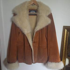 Genuine brown leather with faux fur collar and wrist cuffs. There is a loose button. 