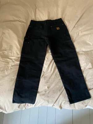 Svarta carhartt doubleknees - Säljer ett par svarta carhartt byxor i nyskick, köpta för 800. Sitter mer som en 32 i midjan! Köparen står för frakt :)