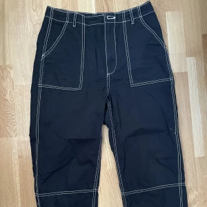 Byxor  - Svarta byxor med vit tråd. Midjemåttet rakt över är 38cm och innerbenslängden är 63cm