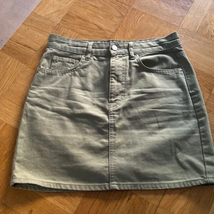Grön jeanskjol - Grön jeanskjol från Gina Tricot, st 36. Sparsamt använd. Aningen sliten runtom knappen annars i jättefint skick. 