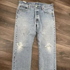 Jättefina Levi’s 501 i mörk tvättad färg, slitningar på knäna och storlek W34L30