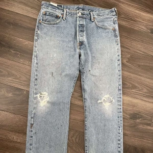 Vintage Levis 501 - Jättefina Levi’s 501 i mörk tvättad färg, slitningar på knäna och storlek W34L30