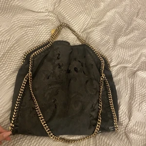 stella mccartney  - svart stella mccartney väska! väskan är väldigt sliten som man ser på bilden därav pris mn fortfarande användbar! självklart äkta! som man ser så har väskan haft något form av mönster men det har skafts bort typ! nypris 11000 men säljer för 800kr.