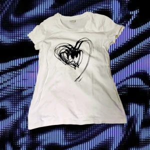 T-shirt med hjärt-tryck - T-shirt med mörk-blått hjärt-tryck. Väl-använd men i gott skick!