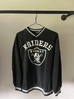 En svart tröja med trycket ”Raiders” på. Vilket jag tror är ett lag i amerikansk fotboll 🏈. Den är köpt på hm. Storlek xs. Och den är i väldigt fint skick! 🤩