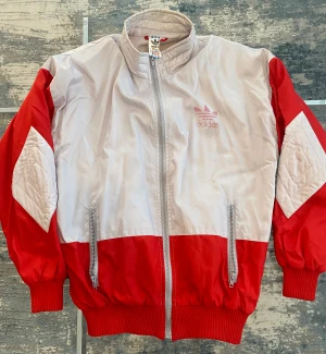 Adidas röd jacka  - Bredd: 58cm Längd: 67cm Helt okej skick. Sitter mer tight mot midjan