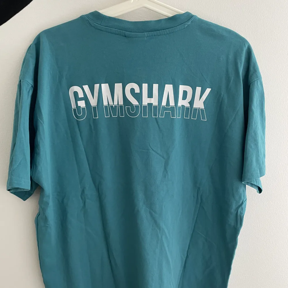 Snygg Gymshark t-shirt med tryck på ryggen. Använd några enstaka gånger och är i väldigt gott skick. Nypris 299. Lite skrynklig för den har legat i garderoben 🙃. Sport & träning.