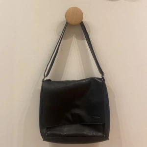 Svart väska  - Rymlig väska i skinn, har justerbart band.