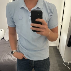 MONCLER PIKÉ - LJUSBLÅ - Säljer denna pikétröjan från märket moncler. Den är i nyskick, inköpt för 2600 kr på NK. Storlek M passar L också.