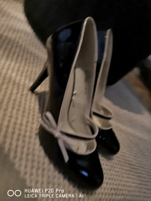 Helt nya höga pumps stl41 - Helt nya höga, ca11cm, pumps i lack svarta m beige kanter & detaljer som en liten rosett. 