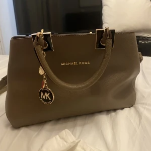 micheal kors väska - Handväska i brun. Använd 2 ggr , gåva av släkting så äkthet kan ej lovas. Jätte fint skick och medel stor