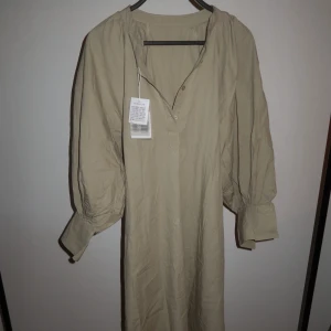 Beige klänning - Oanvänd klänning i beiget. Det är One size på klänningen, men jag som vanligtvis ligger kring storlek XL/46 kan ha denna. Jag är 167 lång och denna klänning går ner till mina knäveck. 