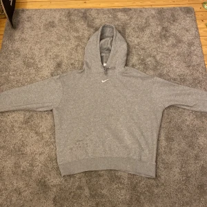 Nike essential hoodie grå - Nästan helt ny Nike hoodie har använd den ett få tal gånger men den är fortfarande i bra kondition 7.5/10 kondition Ny pris 750kr.                                  Nyhet fläckarna är borta.