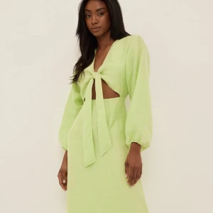 Grön klänning na-kd  strl 34, NY! - Säljer denna häftiga och snygga klänning, endast använd en gång. Storlek 34. Det finns en gömd dragkedja längs sidan, knytet vid bröstet går att reglera.   Nypris: 679 kr. Mitt pris: 200 kr.  Köparen står för frakten!