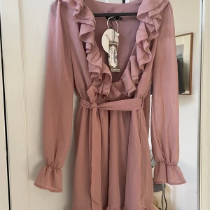 Söt klänning stl s - Ny med lapparna kvar . Gammelrosa färg . Djup urringning 