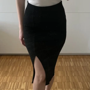 Ribbstickad svart kjol Gina Tricot - Svart ribbstickad kjol från Gina Tricot med slits på ena sidan. Storlek M. Kjolen är endast använd 1-2 gånger och är i nyskick. 