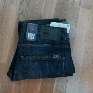 G-star jeans - Säljer nu ett par helt nya G-star RAW jeans marinblå.  Butikspris är 1449kr Jätte fina jeans med snygga detaljer, säljer eftersom dem är något för stora i midjan. Skriv priv för fler frågor! (Köpare står för frakt)