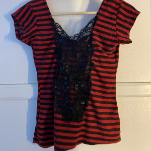 topp  - en svart och röd randig topp med spetsmönster vid bröstkorgen! Går ner i ryggen! Aldrig använd. 
