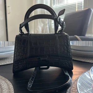 Balenciaga Hourglass XS Top Handle Bag, Black - Dimensions: Widht: 20cm Height: 12,5cm Depth: 7.5cm Strap: 59cm Handle: 7cm  Pris kan diskuteras!