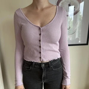 Lila croppad kofta  - Lila croppad kofta från H&M, storlek S. Använd 1 gång. Har en lös liten tråd på insidan i ryggen från prislappen, inget som syns på utsidan när man har den på sig.