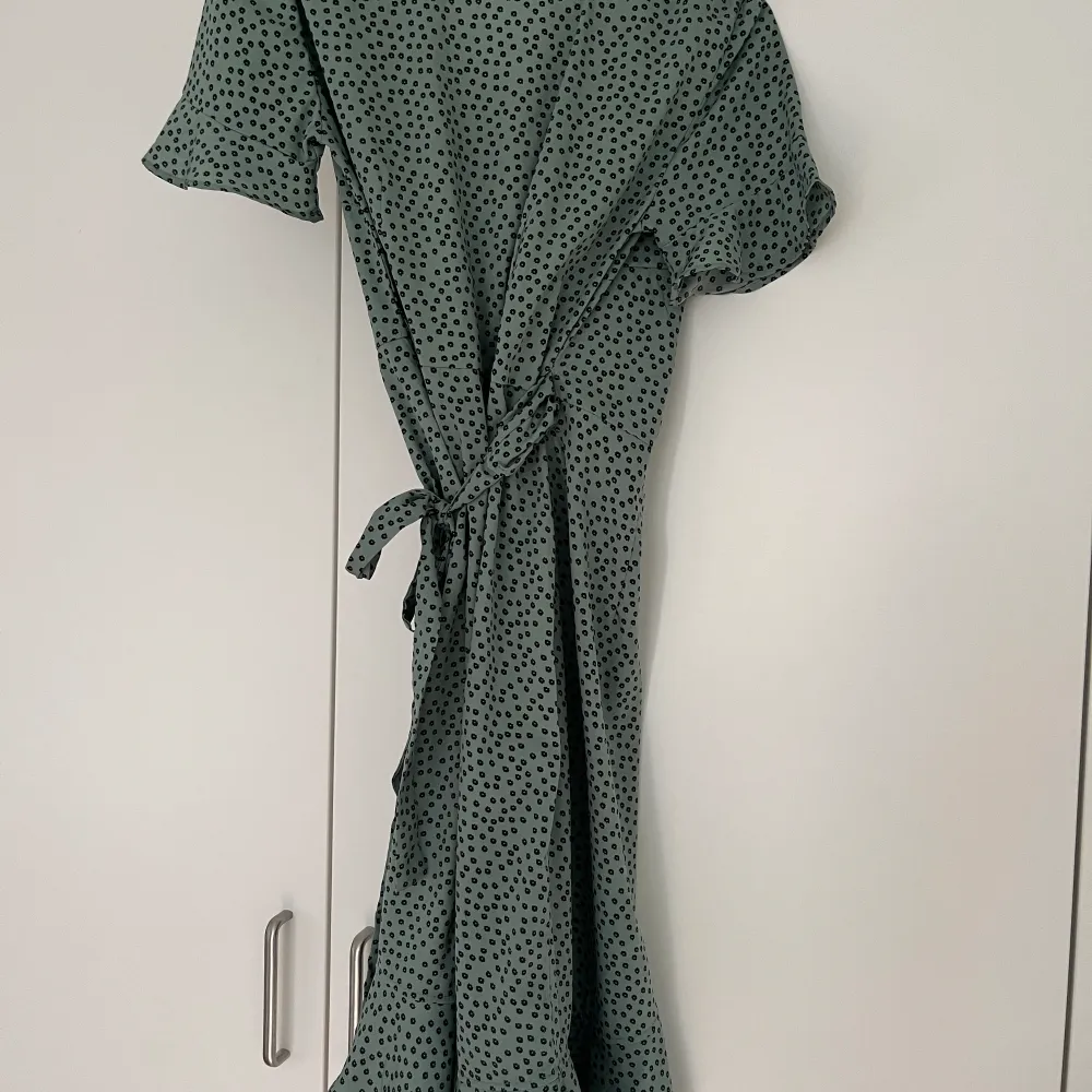 Grön omlottklänning från ONLY som aldrig blivit använd då den är för stor så den är i mycket bra skick. Klänningen går lite längre än knäna på mig och jag är 165. Originalpris: 330kr. Klänningar.