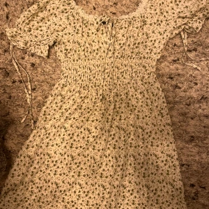 Sommarklänning  - Blommig sommarklänning, endast prövad. Olivgröna blommar.
