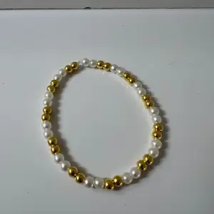 Helt nytt armband med vita och guldiga pärlor 