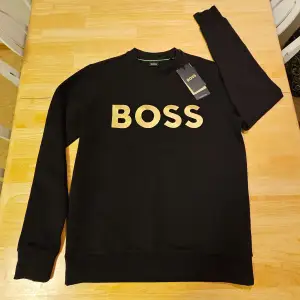 Helt ny Hugo Boss tröja i strl XS.  Super snygg svart tröja med texten som är i guld broderat på bröstet. Etiketten kvar, endast provad en gång men sedan dess legat i garderoben. Och tyvärr kan jag inte returnera för att de gått för lång tid.