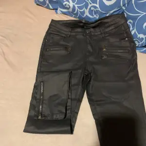 Svarta lite glansiga jeans med detaljer dragkedjor fram dragkedjor nere vid foten stretch storlek M men passar mindre L med