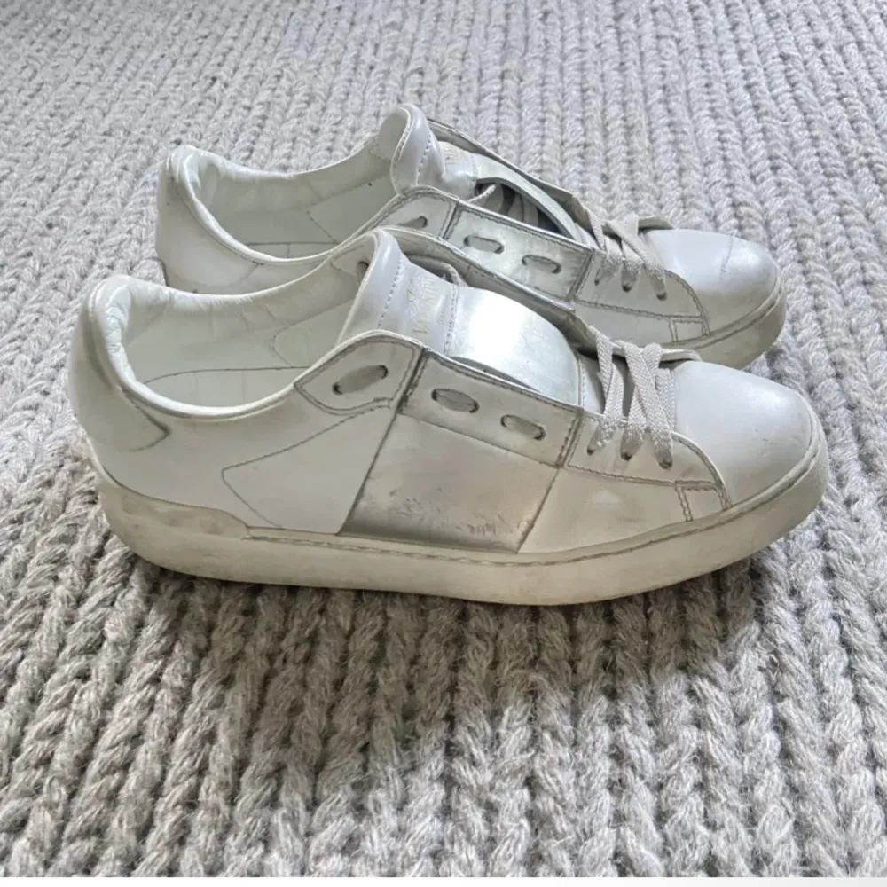 Ett par valentino garvani open sneakers med silver band, köpta på My Theresa. Använda men i gott skick. Kommer med dustbag men saknar låda och kvitto mm. Skor.