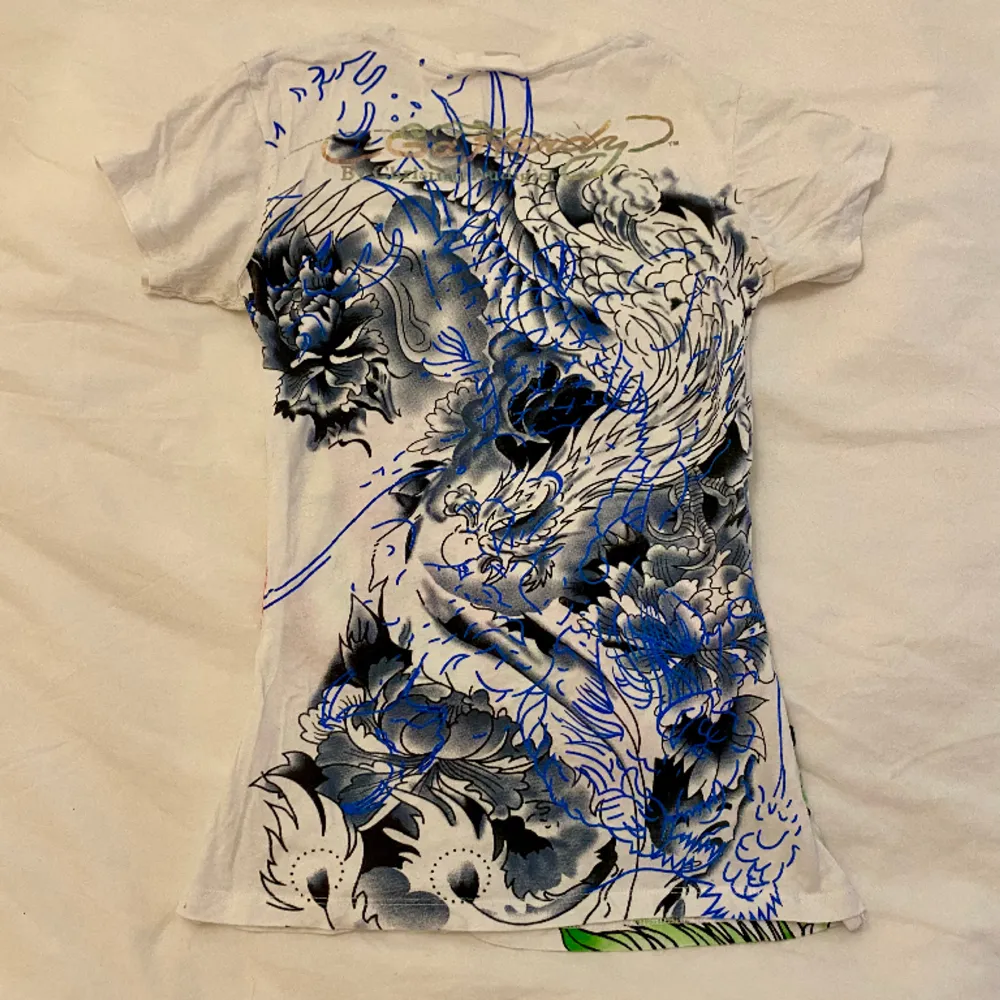 En ascool Ed Hardy t-shirt med ett ballt mönster🐉Den är i storlek L men skulle snarare säga att den passar S för har sytt in den i midjan (har dock inte klippt bort innertyget så om man vill ha den större är det fullt möjligt!) Cool och unik!🌟. T-shirts.