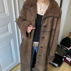 Vintage pälskappa - Jättecool vintage lång mocka/ pälsjacka. Tillhörande skärp finns. Köpt second hand men i jättebra skick. Stl 46 men passar mig som är S. Pris kan diskuteras. Frakt tillkommer men kan annars mötas upp vid Medborgarplatsen i Stockholm. 