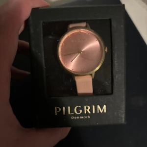 Pilgrim klocka - Super fin och stilren klocka ifrån pilgrim som är helt oanvänd. Rosa med guld detaljer. Fick den får några år sedan men inte använd. 