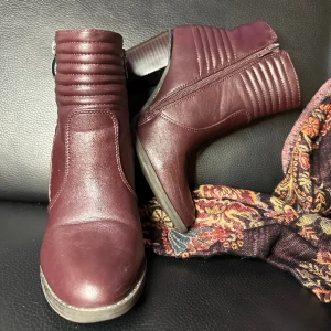 Snygga högklackade vårboots i fint skick Bekväma Fynd Biker - Snygga och sköna vårboots i mycket gott begagnat skick. Lätt fodrade. 23 cm innerdiameter, Stl 36 i EU höjd 19 cm. Passar dig med 35,5, 36 eller 36,5. 8 cm klack, faux leather, mörk vinröd färg. Ett riktigt fynd, mycket sparsamt använda. Bekväma. 